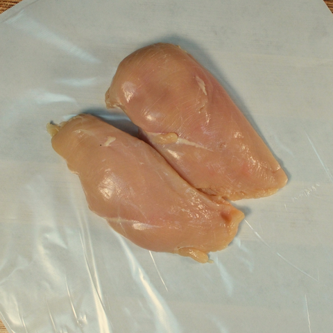 Two trimmed chicken breasts on butcher paper