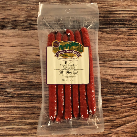Packaged Beef Bacon Cheddar Snack Stix with a label on a wooden surface