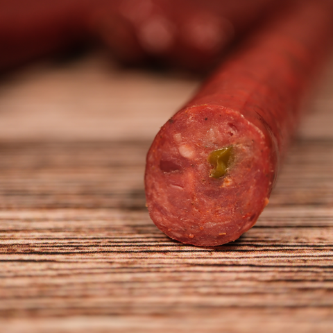 Close-up of a sliced Elk Jalapeno Pepper Snack Stix on a wooden surface