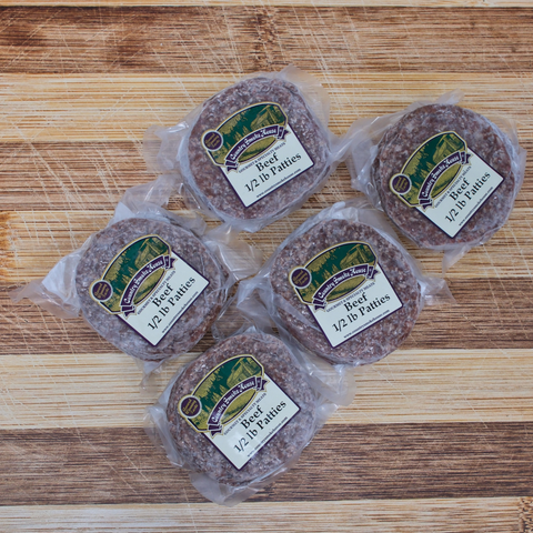 Five packages of half pound beef patties on a wooden surface
