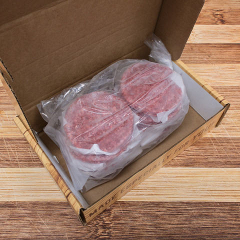 Twelve Quarter Pound Steak And Chuck Patties in a box on a wooden surface.