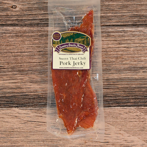Packaged sweet Thai chili pork jerky on a wooden surface with a label.