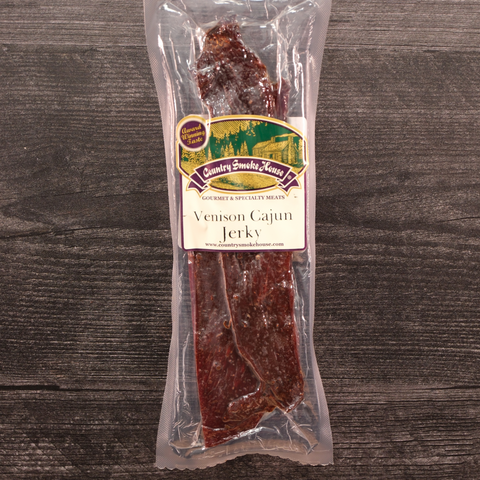 Packaged Venison Cajun Jerky with a label on a wooden surface
