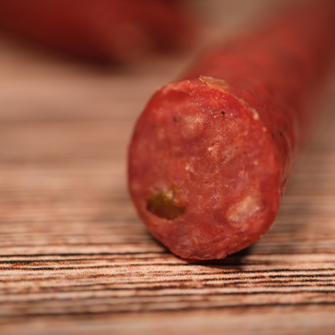Close-up of a sliced Venison Jalapeno Pepper Snack Stix on a wooden surface