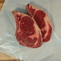 Bone In Ribeye Steaks on a white paper background