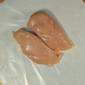 Two trimmed chicken breasts on butcher paper
