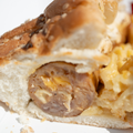 Close-up of a sliced Bacon, Mac & Cheese Brat on a bun