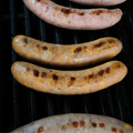 Grilled Bacon, Mac & Cheese Brats on a grill with visible grill marks.
