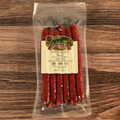 Packaged Beef Bacon Cheddar Snack Stix with a label on a wooden surface