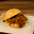 Southern Style Shredded Beef Brisket Sandwich on a white plate with a wooden background