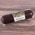 Packaged beef hickory salami chub on a wooden surface.