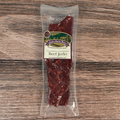 Packaged beef jerky with a label on a wooden surface
