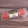 A packaged beef salami chub on a wooden surface.
