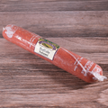 A packaged Buffalo Long Salami on a wooden surface.