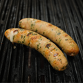 Two Spinach Feta Chicken Brats cooking on a grill with grill marks.