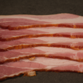 Close-up of sliced Premium Sugar Cured Double Smoked Bacon on a dark surface