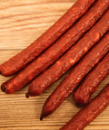 Smoked duck jalapeno cheese snack sticks on a wooden surface