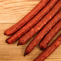 Smoked duck jalapeno cheese snack sticks on a wooden surface