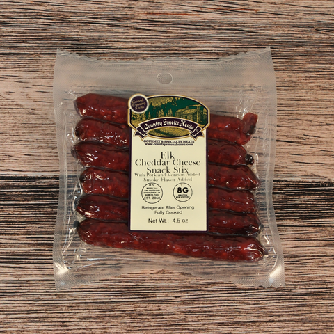 Packaged elk cheddar cheese snack sticks with a label on a wooden surface