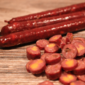 Sliced Elk Cherry Cheddar Snack Stix on a wooden surface.