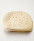 A stack of round, pale yellow cheese slices with small holes, photographed on a clean white background.