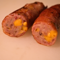 Close-up of a sliced Loaded Baked Potato Brat with cheese inside on a cutting board