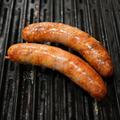Two Loaded Baked Potato Brats cooking on a grill