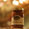 Jar of Mild Summer Salsa on a wooden surface.