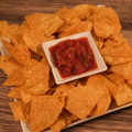 Platter of tortilla chips with a bowl of Mild Summer Salsa on a wooden surface