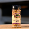 A bottle of Montreal Burger & Steak Rub seasoning on a wooden surface.