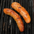 Two Mushroom & Swiss Brats cooking on a grill