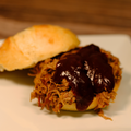 Slider with pulled pork and Ole Smokey BBQ Sauce on a white plate with a wooden background