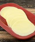 Thin round slices of pale yellow cheese arranged on a red rectangular serving platter, set on a dark wood surface.