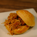 A Southern Style Hand Pulled Chicken sandwich on a white plate with a wooden background