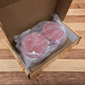 Twelve Quarter Pound Steak And Chuck Patties in a box on a wooden surface.