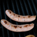 Two Russian Reuben Brats on a grill with grill marks.