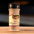 A bottle of Steve's All Purpose Seasoning with 50% Less Salt on a wooden surface.