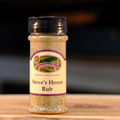 A bottle of Steve's House Rub seasoning on a wooden surface.
