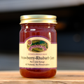 A jar of Country Smoke House Strawberry-Rhubarb Jam on a wooden surface.