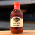 A bottle of Sweet Heat BBQ Sauce on a wooden surface.