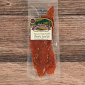 Packaged sweet Thai chili pork jerky on a wooden surface with a label.