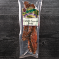 Packaged turkey peppered jerky with a label on a dark wooden surface