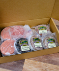 A Variety of Gourmet Burger Patties in a box on a wooden surface.