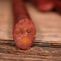 Close-up of a venison cherry cheddar jalapeno snack stick on a wooden surface
