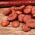Sliced venison cherry cheddar jalapeno snack stick pieces on a wooden surface