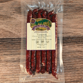 Packaged Venison Cherry Cheddar Jalapeno Snack Stix with a label on a wooden surface