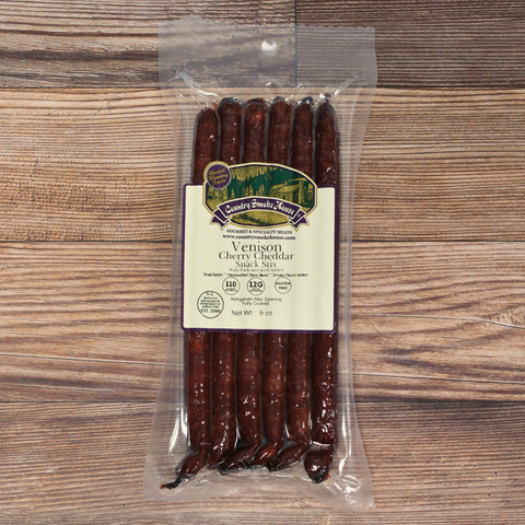 A package of Venison Cherry Cheddar Snack Stix on a wooden background.