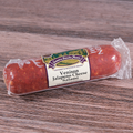 Packaged Venison Jalapeno Cheese Salami Chub on a wooden surface.