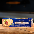 A box of Wellington Traditional Water Crackers displayed on a wooden surface.