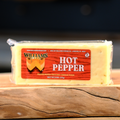 A packaged block of William's Hot Pepper Cheese on a wooden surface.
